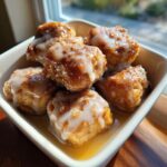 A small bowl filled with gooey cinnamon roll bites topped with white glaze icing.