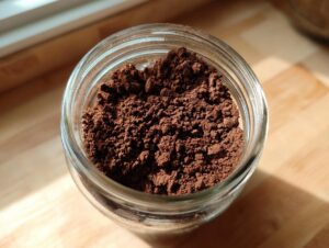 Overhead shot of rich, dark brown homemade hot cocoa mix stored in a small glass jar.