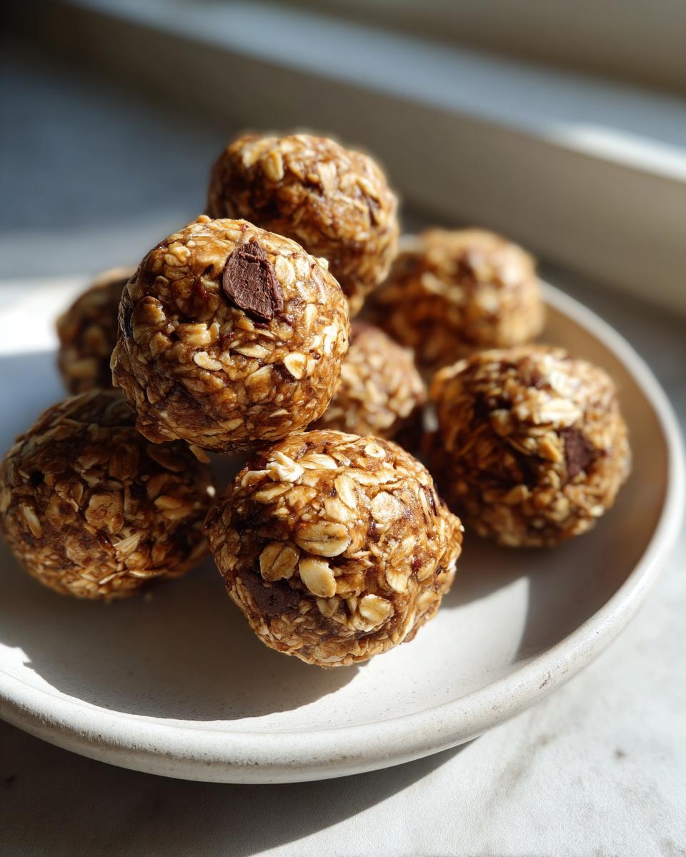 A stack of homemade, oat-based protein balls with visible chocolate chips resting on a small white plate.