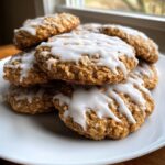 A close-up stack of freshly baked iced oatmeal cookies topped with a thick white glaze.