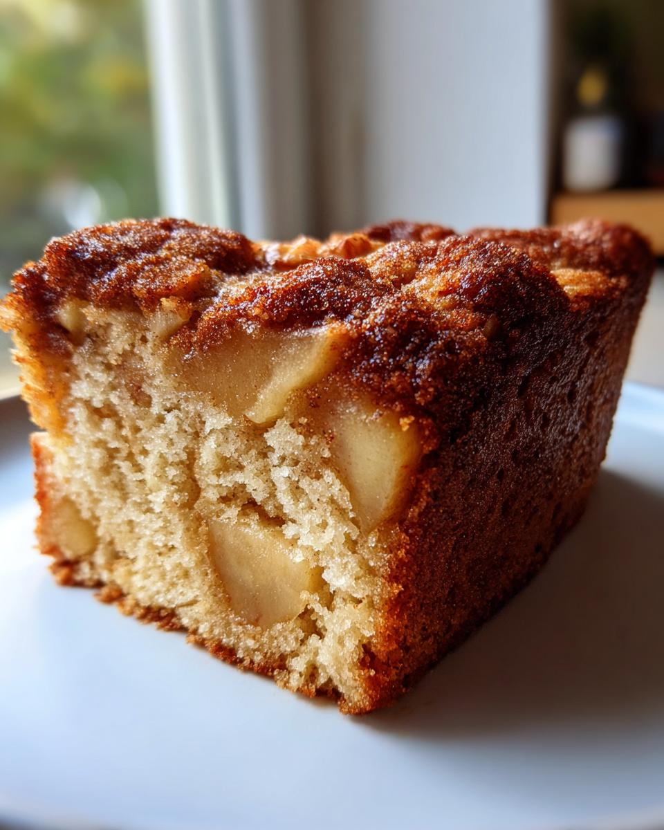 Close-up of a moist slice of jewish apple cake showing tender crumb and baked apple pieces.