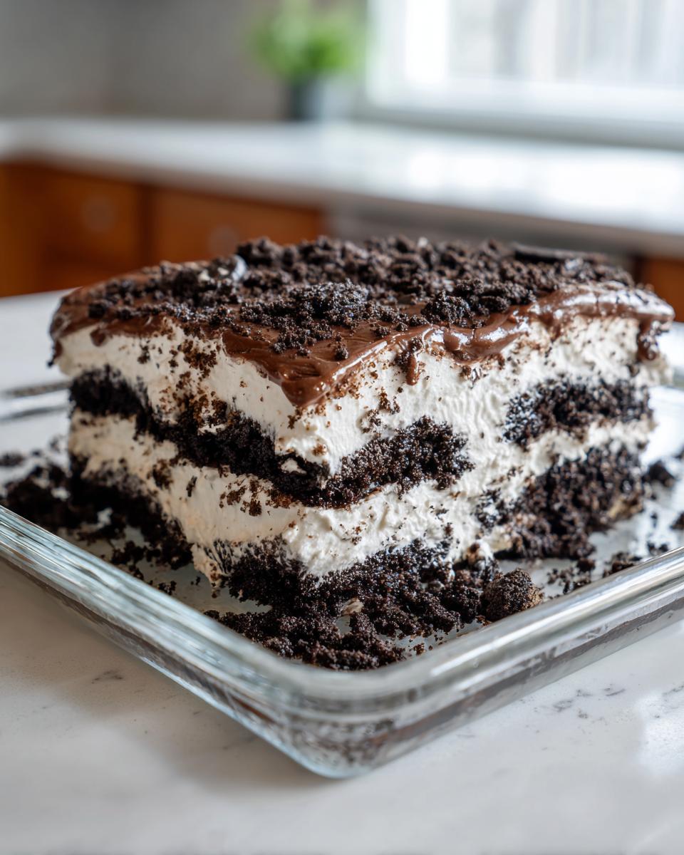 A close-up of a layered slice of Oreo dirt cake showing rich chocolate cookie crumbs and white cream filling.