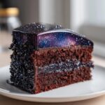 A rich slice of dark chocolate capricorn cake topped with a stunning galaxy mirror glaze.
