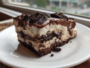 A rich, layered slice of dirt cake featuring chocolate cookie crumbs and creamy filling, topped with chocolate frosting.