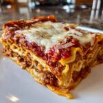 A close-up view of a hearty slice of lazy lasagna, layered with pasta, meat sauce, and melted mozzarella cheese.