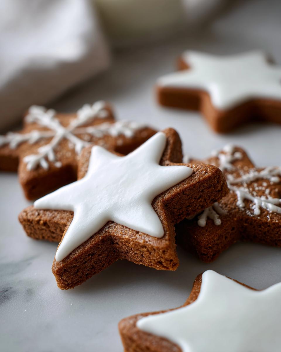 Close-up of several star-shaped soft gingerbread cookies decorated with smooth white icing.