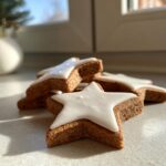 Close-up of several soft gingerbread cookies shaped like stars, topped with smooth white royal icing.