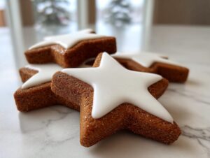 Close-up of several star-shaped soft gingerbread cookies topped with smooth white royal icing.