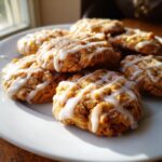 A stack of soft maple brown sugar cookies drizzled generously with white vanilla glaze, sitting on a white plate.