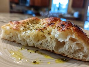 Close-up of the airy, open crumb structure of baked sourdough discard pizza dough, drizzled with olive oil.