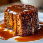 Close-up of a rich, dark sticky toffee pudding recipe portion drenched in thick, glossy toffee sauce.