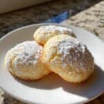 Three golden 3-ingredient butter cookies generously dusted with white powdered sugar on a white plate.