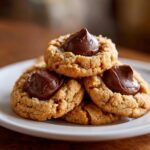 A close-up stack of freshly baked peanut butter blossom cookies topped with rich, melted chocolate.