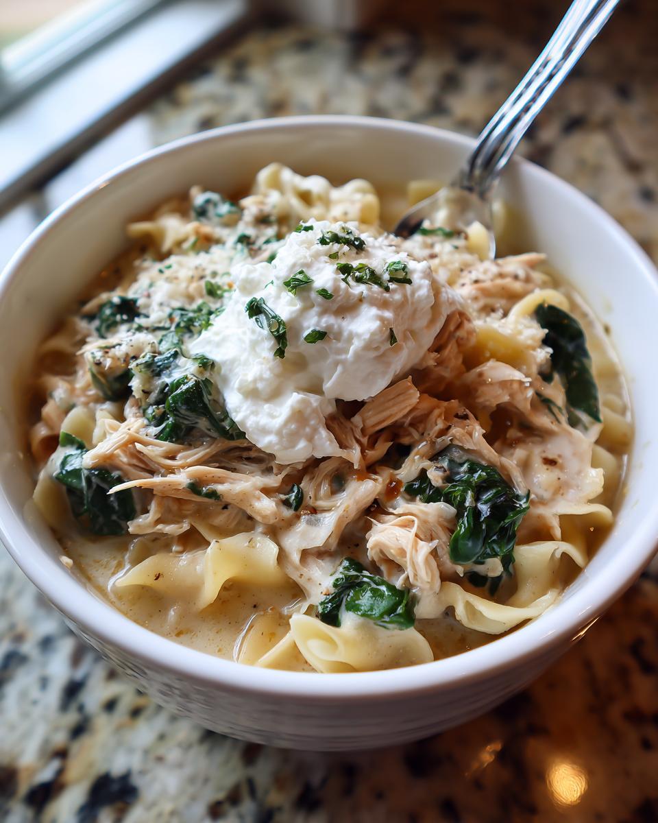 Close-up of a bowl of creamy white chicken lasagna soup topped with ricotta and parsley.