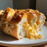 Close-up of warm, pull-apart cheese bread with melted, stretchy cheese oozing out.