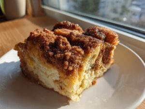 A close-up of a square slice of amazing french toast casserole topped with a thick, sugary cinnamon streusel.
