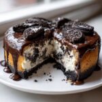 A slice cut from an amazing oreo cheesecake topped with chocolate ganache and whole cookies.