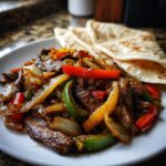 A plate of sizzling steak fajitas mixed with colorful bell peppers and onions, served with warm tortillas.