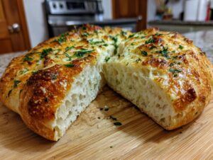 Cross-section view of homemade artisan bread showing a light, airy crumb topped with melted cheese and fresh parsley.