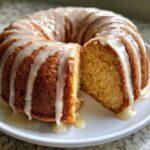 A freshly baked Bacardi rum cake, drizzled with white glaze, with one slice cut out to show the moist interior.