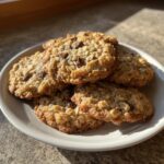 A stack of golden brown banana oatmeal cookies with visible chocolate chips resting on a small white plate.