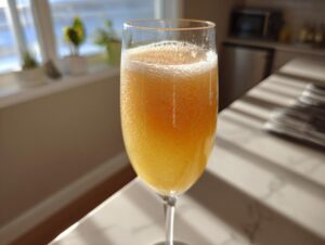 Close-up of a fizzy, orange-hued bellini recipe cocktail served in a champagne flute.
