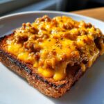 Close-up of a slice of toast topped with a thick layer of melted orange cheese and seasoned meat mixture, typical of a hanky panky recipe.