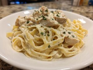 Close-up of a serving of rich chicken fettuccine alfredo pasta covered in creamy sauce and garnished with parsley.