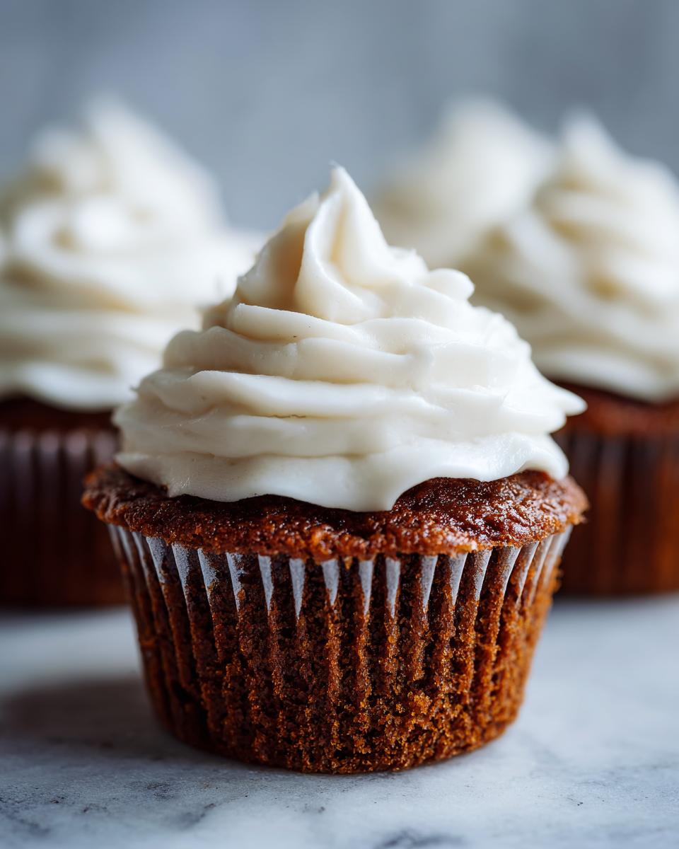 A close-up of one perfectly baked gingerbread cupcakes topped with a swirl of white cream cheese frosting.