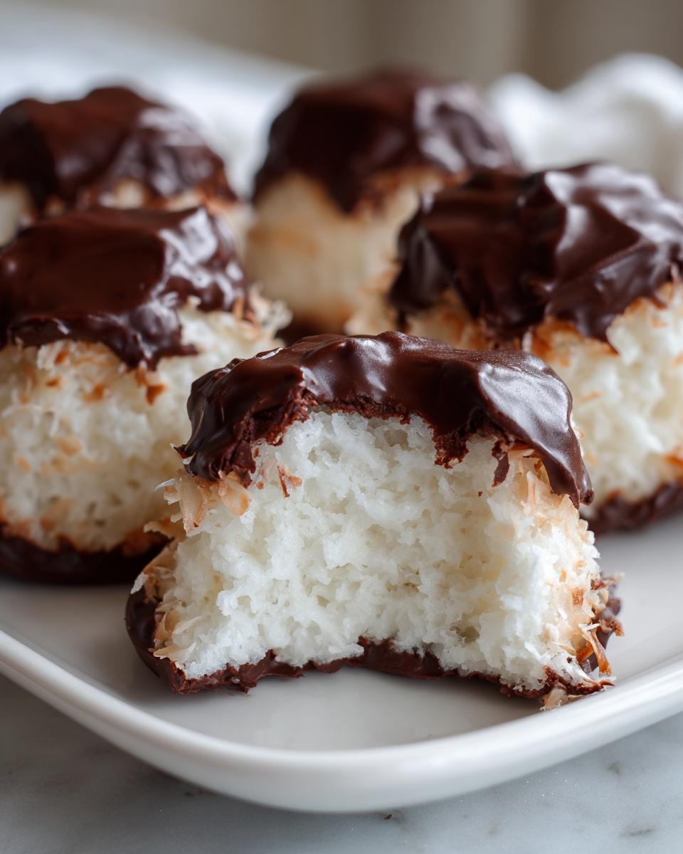 Close-up of a bitten piece of fluffy white cool whip candy dipped in dark chocolate.