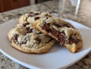 Close-up of soft cream cheese chocolate chip cookies, one broken open showing gooey, melted chocolate chips.