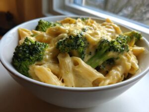 Close-up of creamy broccoli pasta featuring penne noodles coated in a rich cheese sauce with bright green broccoli florets.