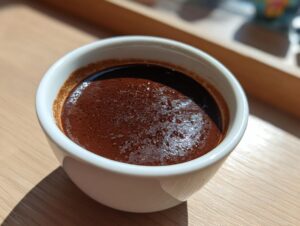 Close-up of rich, dark chocolate pudding with a slight sheen in a small white ramekin.