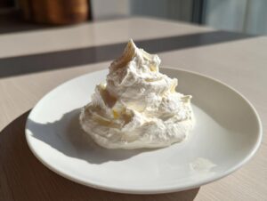 A dollop of thick, white creamy horseradish sauce piped into a swirl shape on a small white plate.