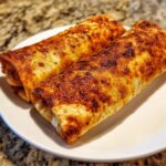 Two golden-brown, crispy Baked Chicken Chimichangas resting on a white plate.