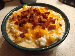 A close-up of a bowl of creamy easy crockpot potato soup topped with melted cheddar cheese and crispy bacon bits.