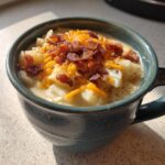 Close-up of a hearty bowl of easy crockpot potato soup topped with shredded cheddar cheese and crumbled bacon.
