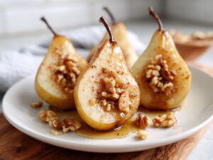 Three halves of sweet baked pears drizzled with syrup and stuffed with walnuts on a white plate.