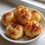 Close-up of several golden brown, breaded potato dumplings served in a small white bowl.