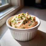 A close-up of thick, creamy remoulade sauce topped with fresh green chives in a small white bowl.