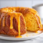 Close-up of a slice cut from a bundt orange juice cake, generously drizzled with thick orange glaze.