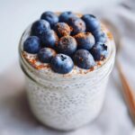 Close-up of creamy chia seed pudding in a jar, topped with fresh blueberries and a sprinkle of cinnamon.