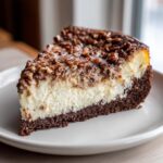 A close-up of a perfect slice of german chocolate cheesecake showing the dark crust, creamy filling, and pecan topping.