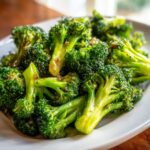Close-up of bright green, perfectly steamed broccoli florets glistening with a light sauce.