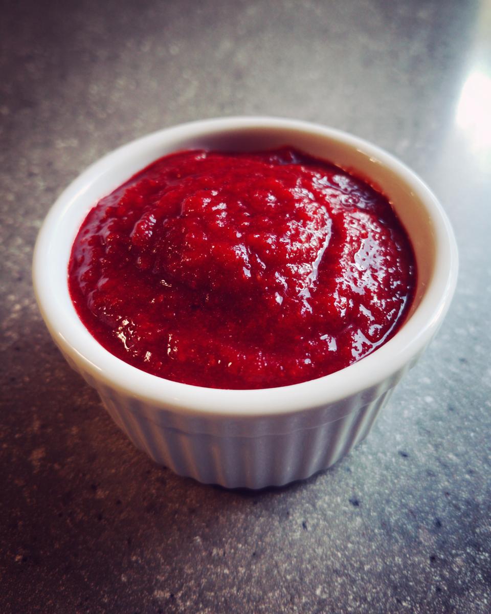 Close-up of vibrant, thick homemade cocktail sauce served in a small white fluted ramekin.
