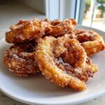 Close-up of freshly fried, golden brown buñuelos generously coated in cinnamon sugar.