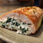 Cross-section view of baked stuffed salmon filled with creamy spinach mixture.