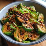 Thickly sliced cucumbers coated in a creamy peanut butter dressing, topped with black sesame seeds and scallions for an asian cucumber salad with peanut butter.