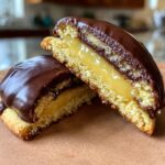 Close-up of boston cream pie cookie bites cut in half showing vanilla cake, pastry cream, and chocolate glaze.