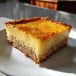 A close-up of a square slice of cassava cake showing the textured base and creamy yellow custard top.